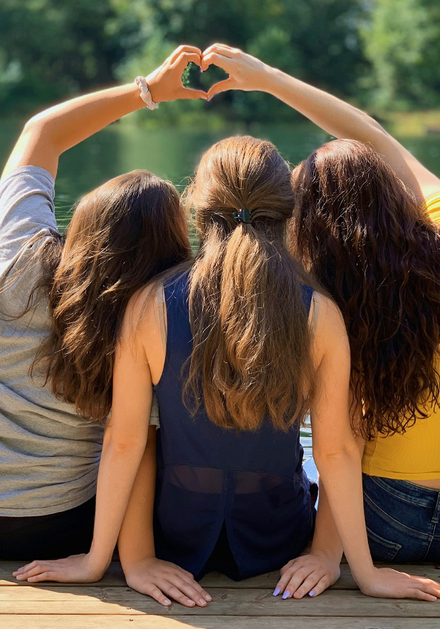 Three women facing away with hands in a heart shape